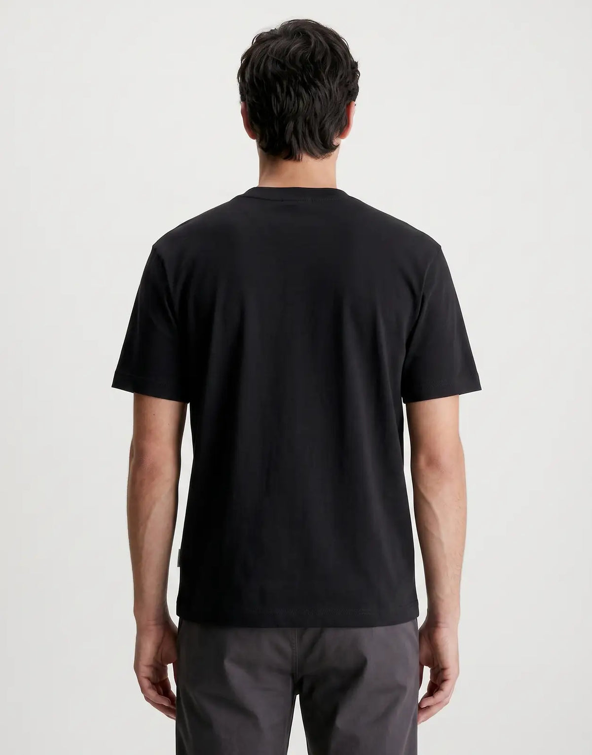 Rear view of the Calvin Klein 16s Tricolor Monologo Graphic Black T-Shirt, showcasing its smooth fabric and short sleeves.