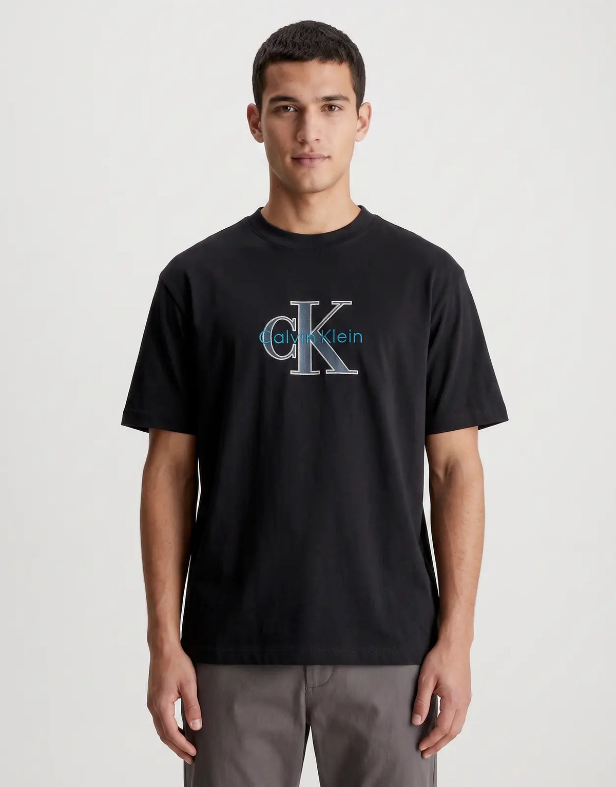 Calvin Klein 16s Tricolor Monologo Graphic Black T-Shirt. A comfortable short-sleeve tee featuring a distinctive blue and