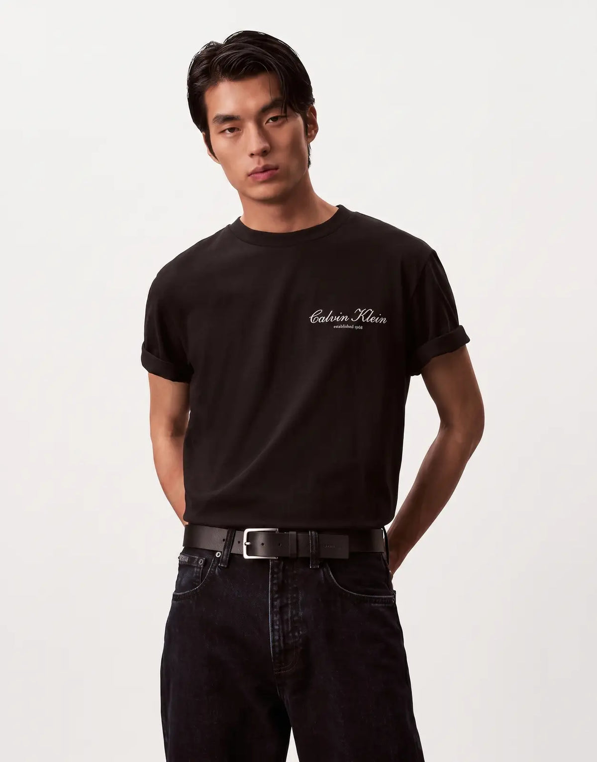 A man models a black Calvin Klein 20s March Graphic Seasonal Fashion T-shirt with a white script logo.