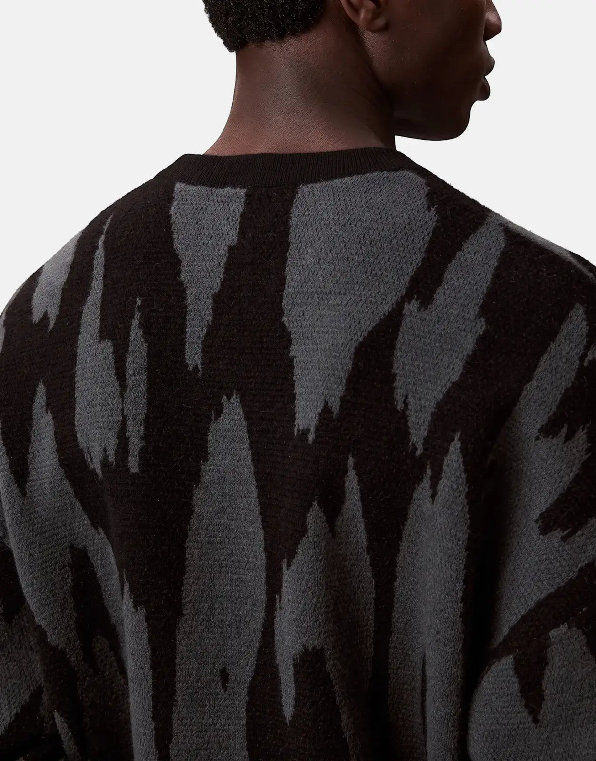 Close-up of a model from the back wearing a black and grey Calvin Klein Abstract Jacquard Sweatshirt with an abstract