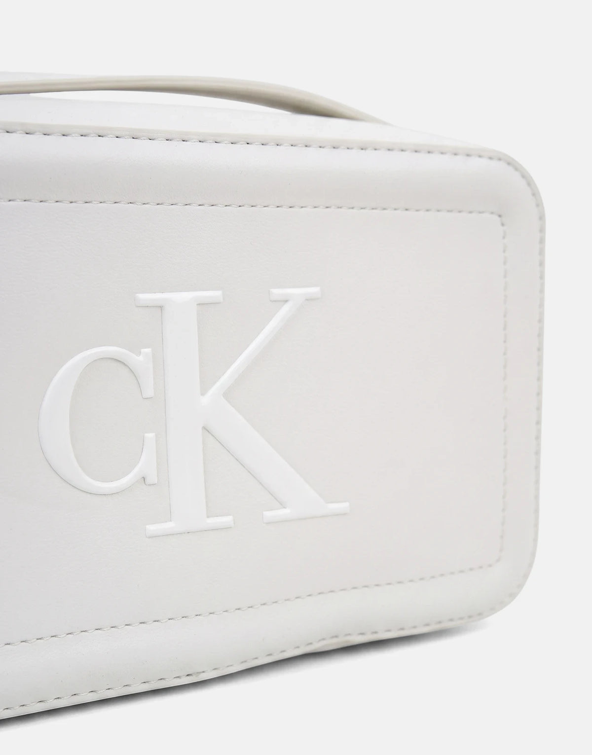 Close-up of a white Calvin Klein Bold CK camera bag, featuring the embossed CK logo on the front and visible stitching