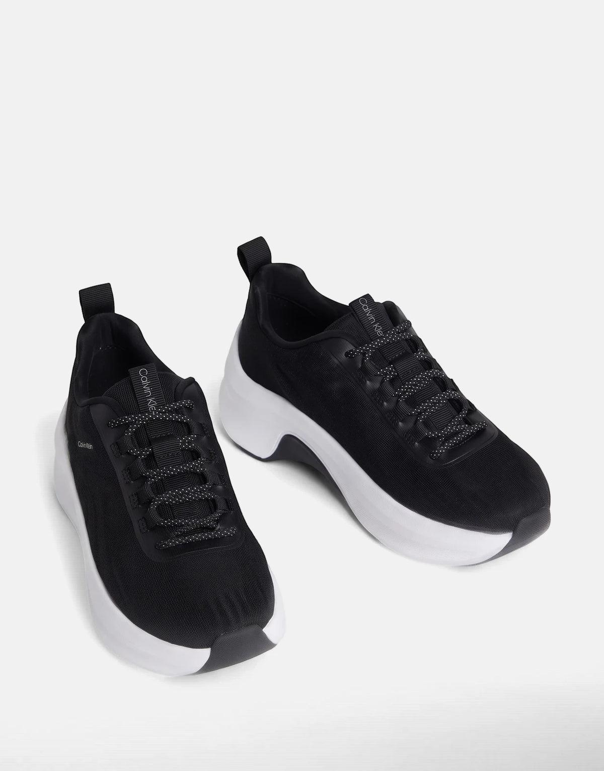 A pair of black Calvin Klein Chunky Run Lacesock Stripe sneakers with thick white soles and speckled laces, floating against