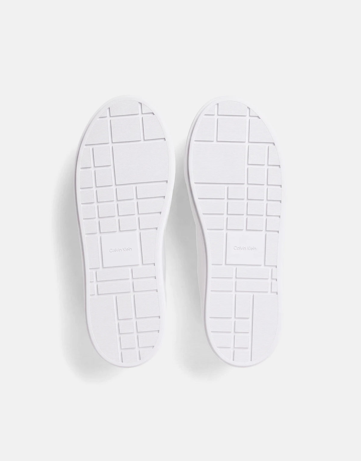 Pair of white Calvin Klein Flatform Laceup sneakers, shown from the bottom revealing the geometric patterned soles.