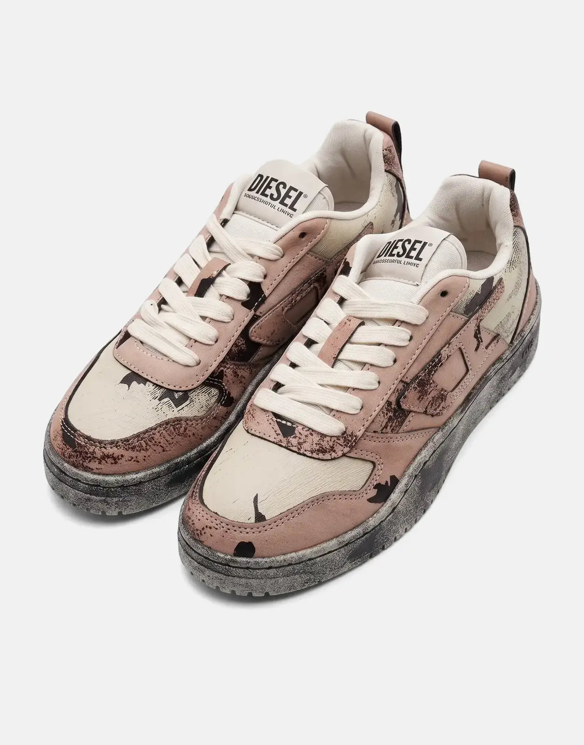 A pair of Diesel S-Ukiyo V2 Low Sneakers with a light pink camouflage pattern and distressed black soles.