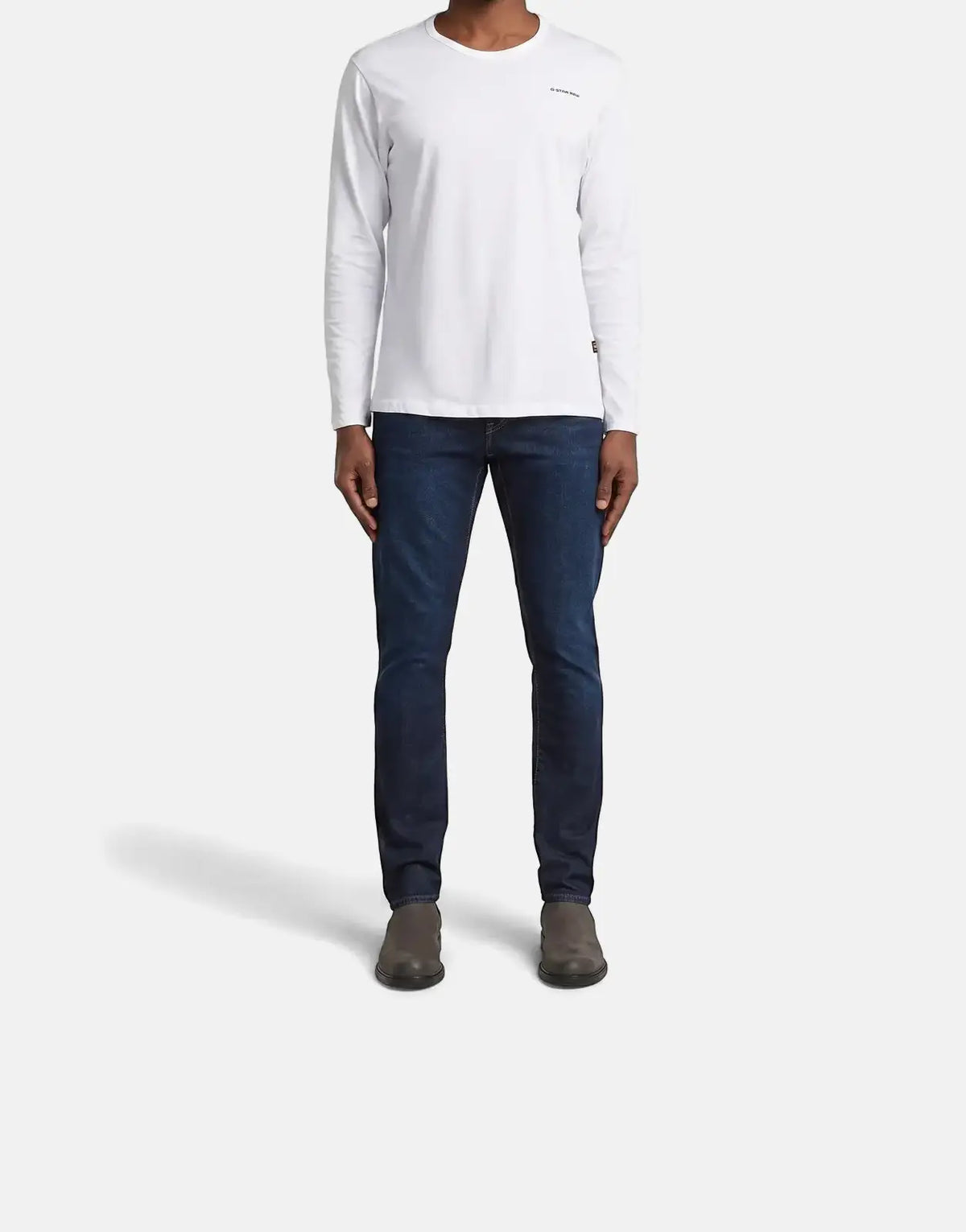 Full body shot of a male model wearing a G-Star RAW 3301 long-sleeve t-shirt and dark blue jeans.