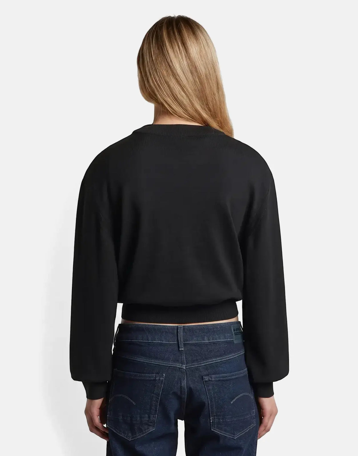 Woman wearing a G-Star RAW Boxy Knit Dk Black sweater and dark blue jeans, viewed from the back.