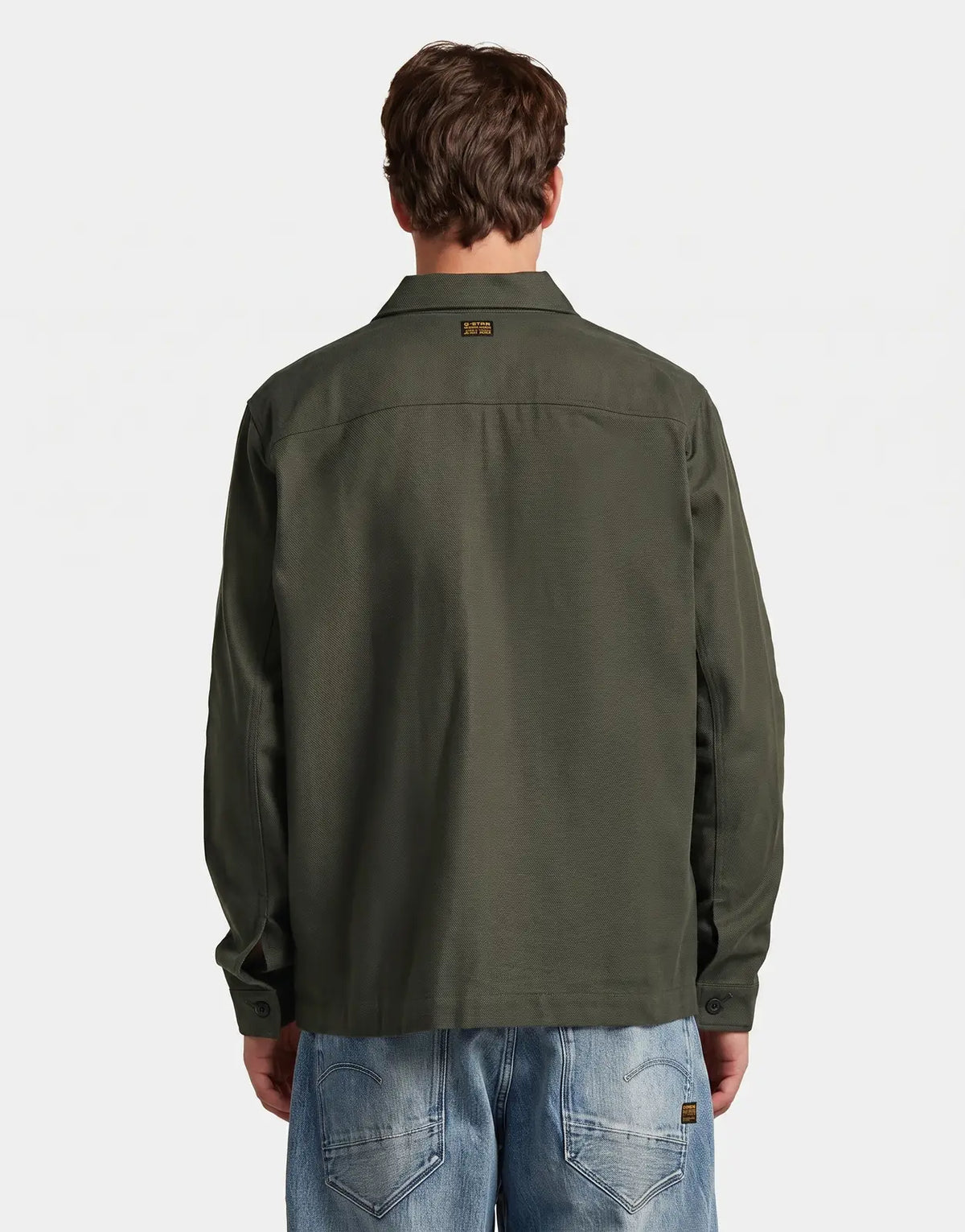 Back view of a man wearing a dark green G-Star RAW Core LW Asfalt Overshirt, featuring its textured fabric and back collar