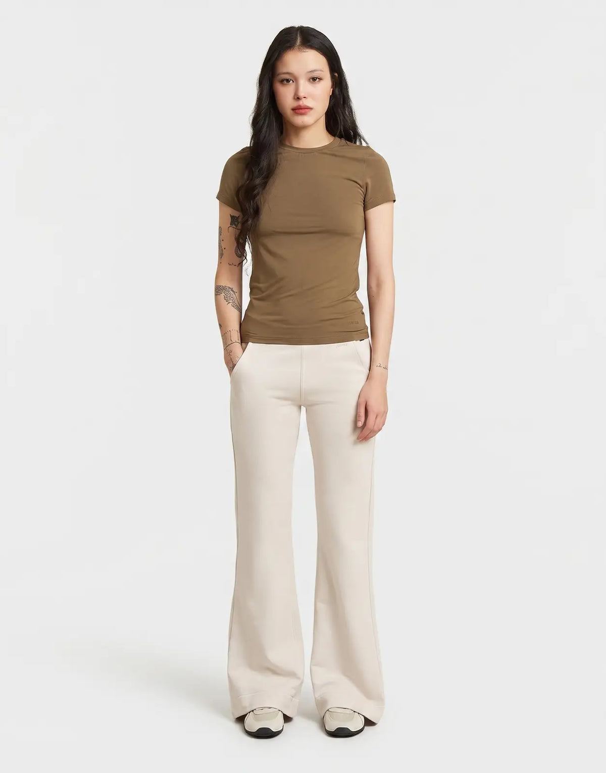 A woman wears G-Star RAW Flared Whitebait Sweatpants, a light off-white color, paired with a fitted brown t-shirt in a