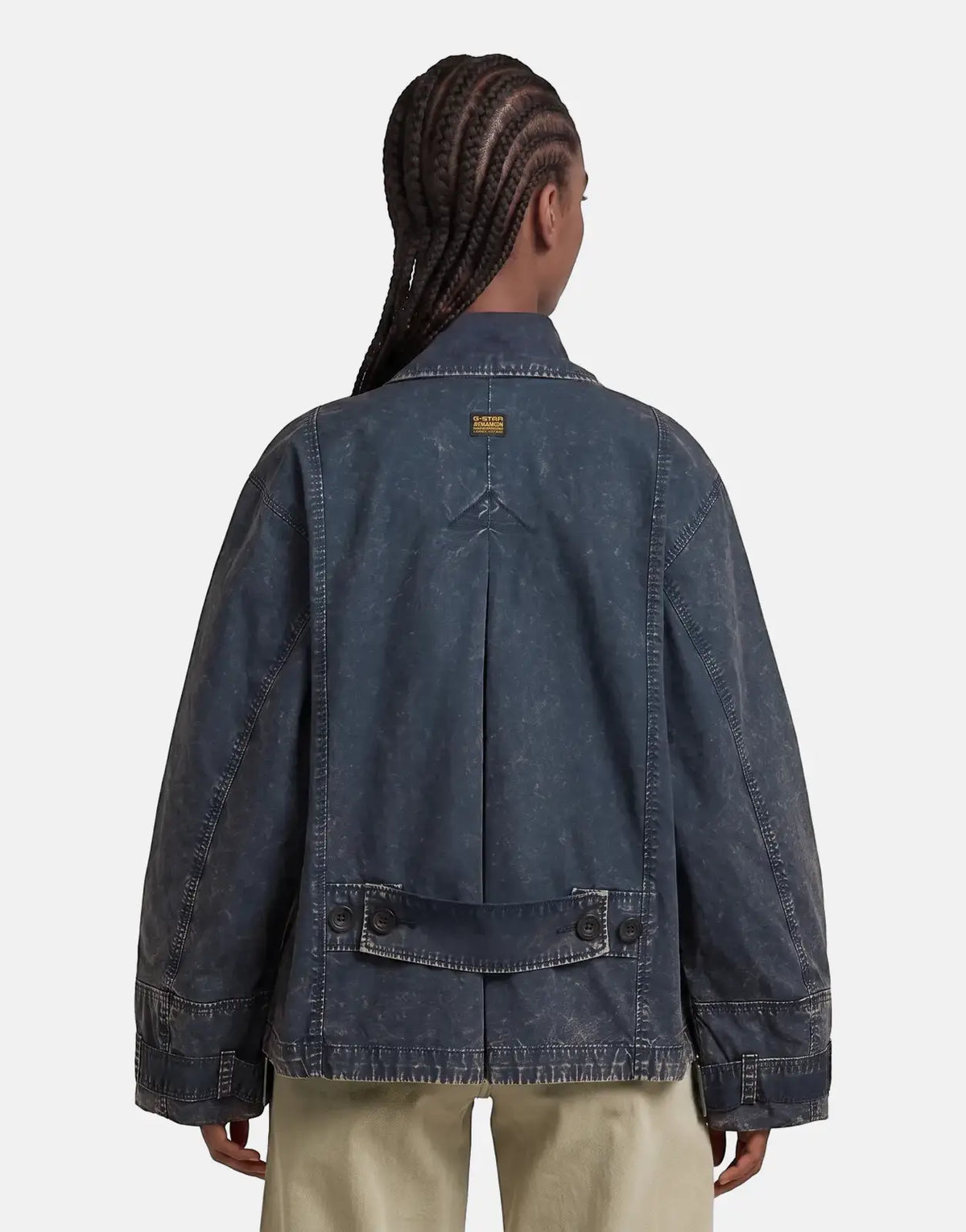 Rear view of a model wearing a G-Star RAW Oversized Short Trench Coat in an overdyed salute dark blue, paired with light