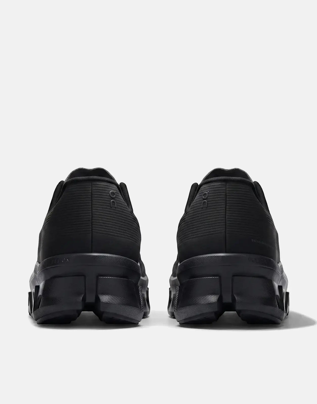 Rear view of two On Men's Cloudmonster Void Black Sneakers, showcasing their black textured design and chunky soles.