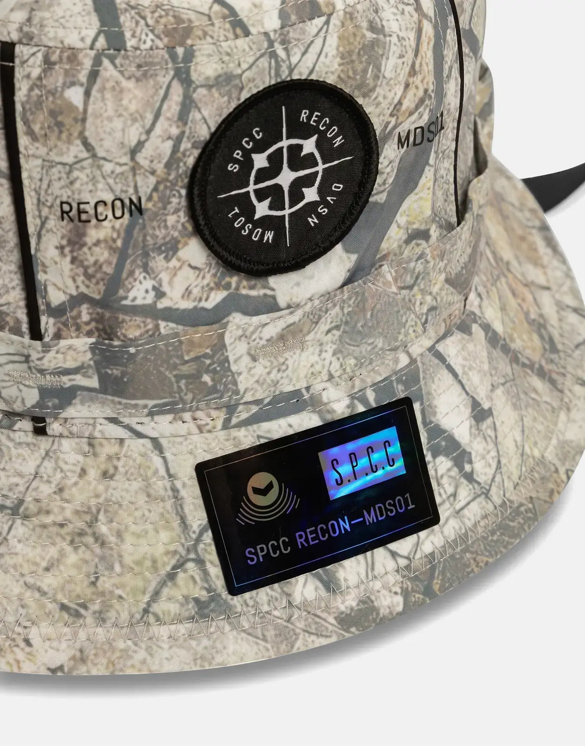 SPCC Recon Incognito Bucket Hat in a camouflage pattern, featuring black circular and iridescent rectangular brand patches.
