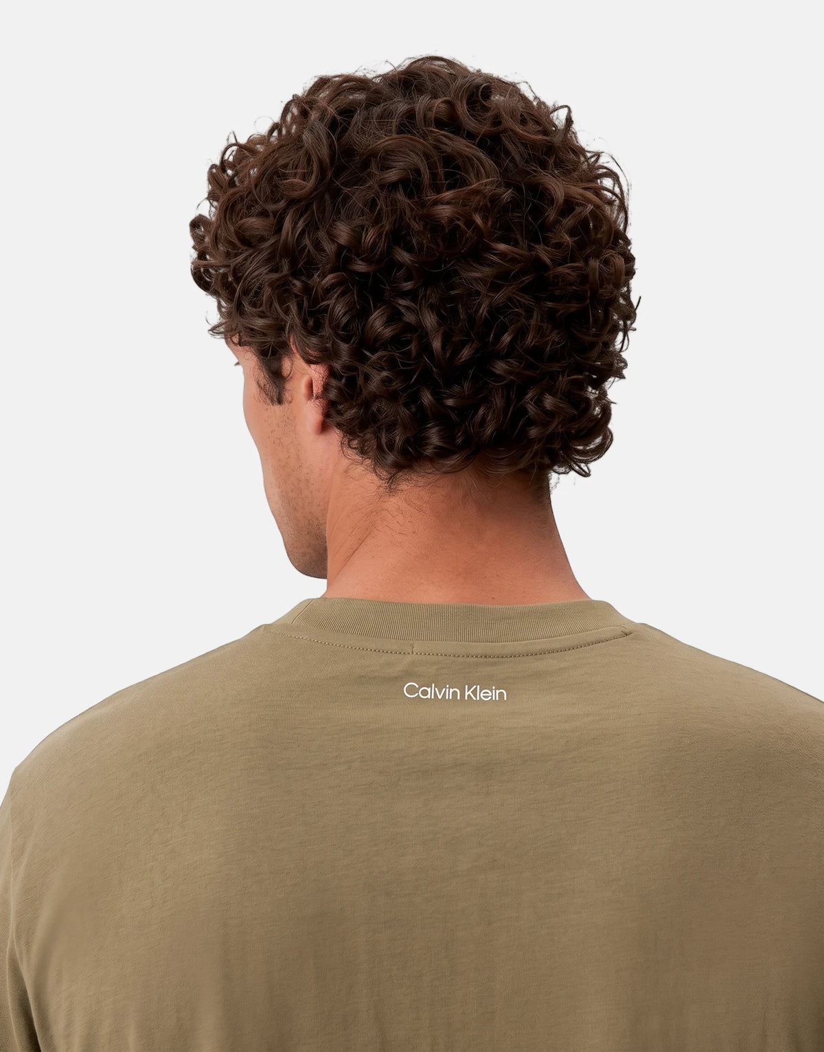 Close-up of a man's back, showcasing a Calvin Klein 20s March Graphic Seasonal green t-shirt with its logo and curly hair.