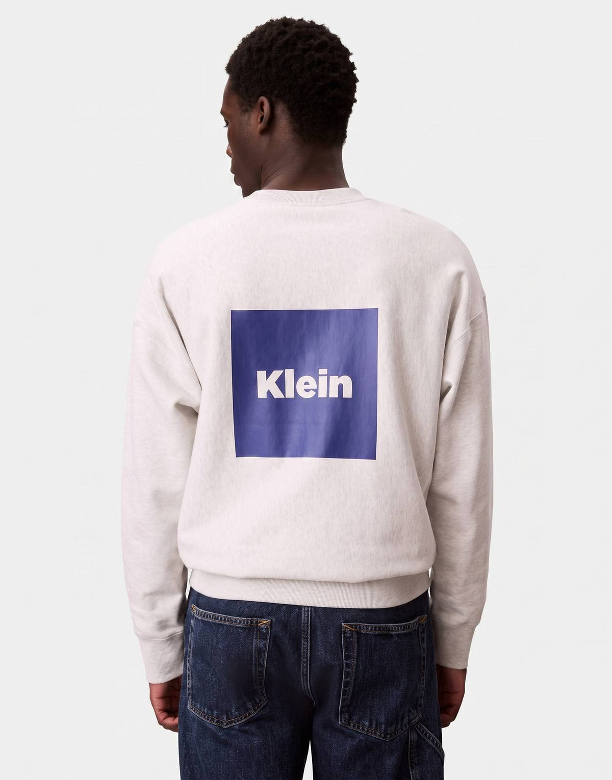 Calvin Klein Box Graphic Sweatshirt in grey, showcasing the distinctive blue 'Klein' box graphic on the back worn by a
