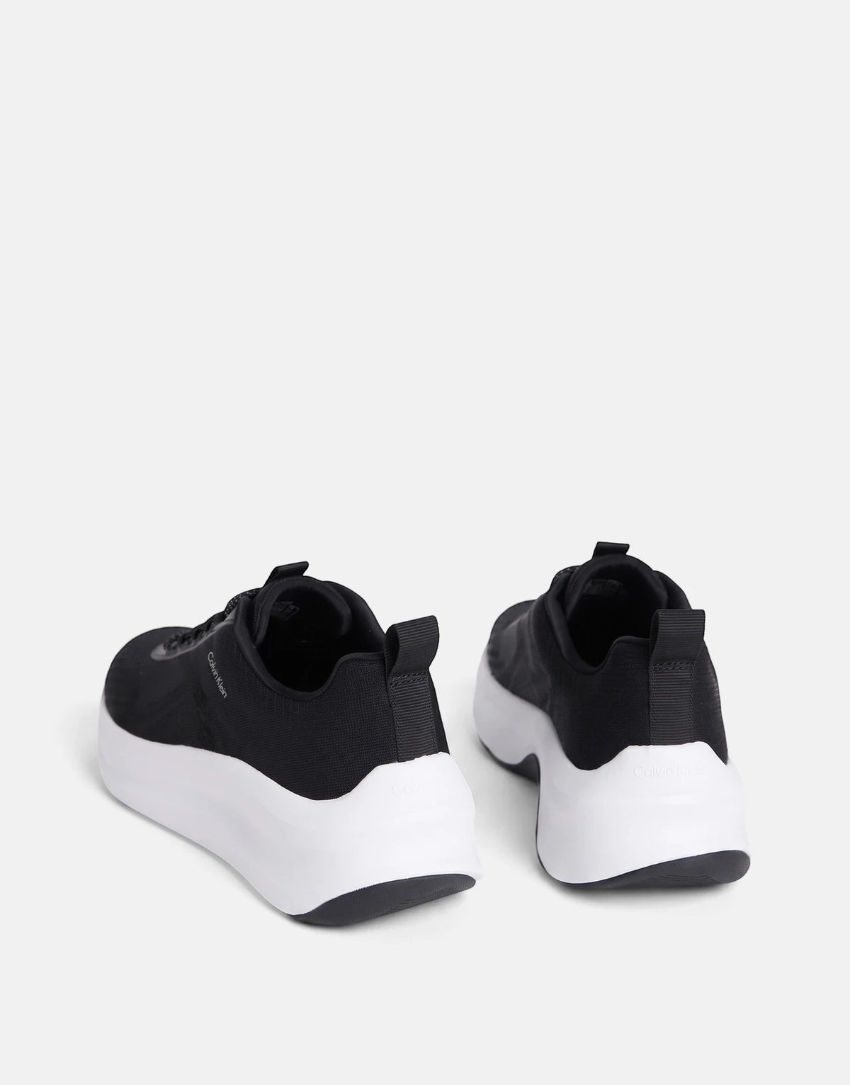 Pair of Calvin Klein Chunky Run Lacesock Stripe sneakers in black with thick white soles, floating and viewed from a rear