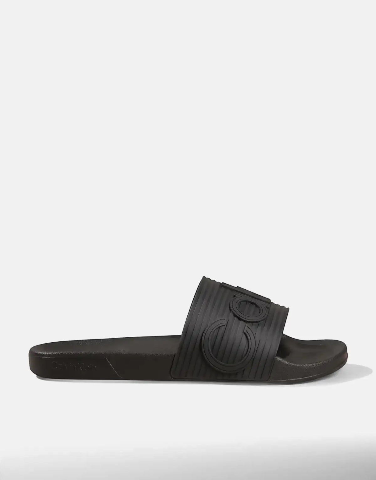 Black Calvin Klein Essential Texture men's slides, displayed from a side angle, featuring a ribbed strap and logo detailing.