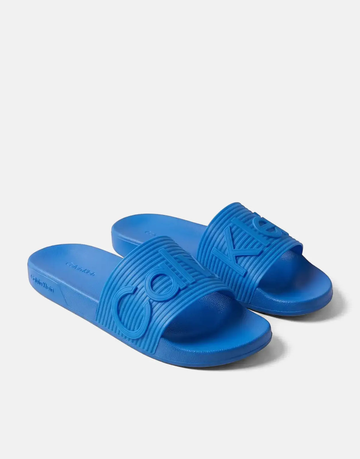 Pair of blue Calvin Klein Essential Texture slides with ribbed straps and embossed logo on a studio background.