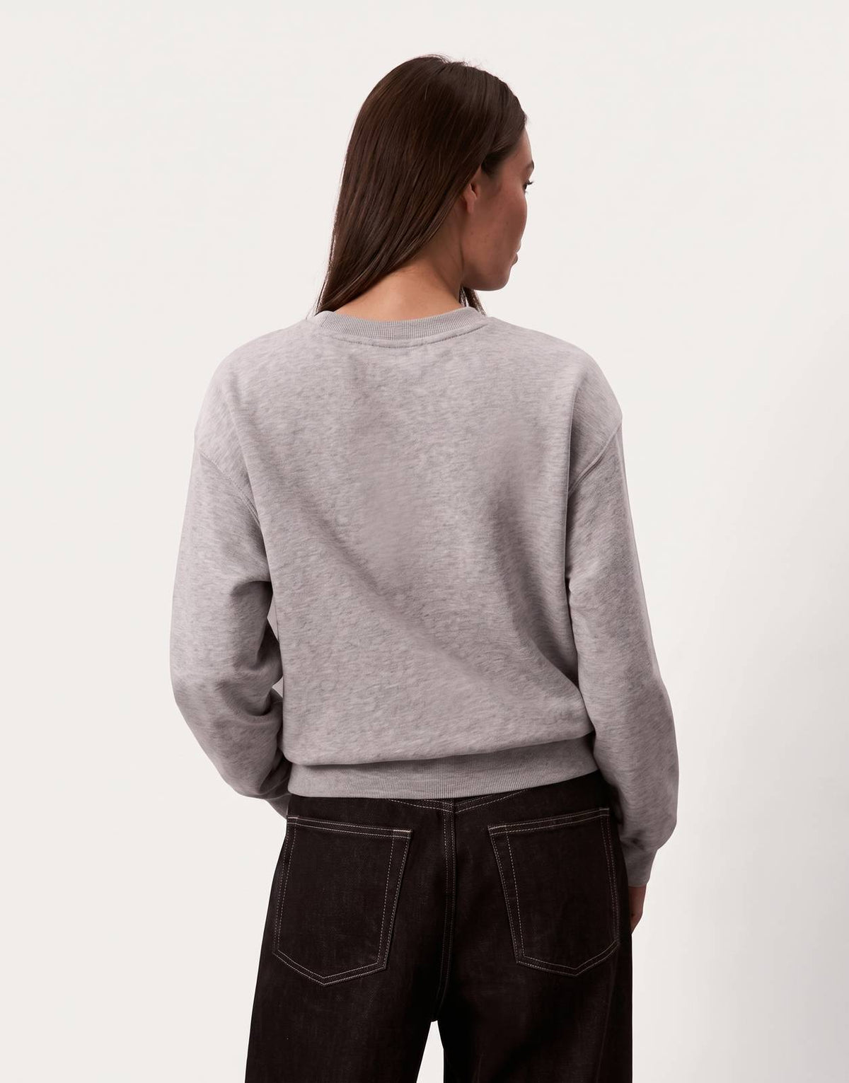 A model from the back wearing a Calvin Klein Foil Monologo French Terry Relaxed Grey Sweatshirt paired with dark jeans.