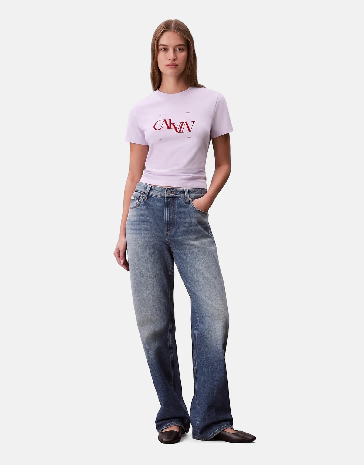 Full body shot of a woman wearing a Calvin Klein Seasonal Graphic Slim Lilac T-Shirt, blue wide-leg jeans, and black flats,