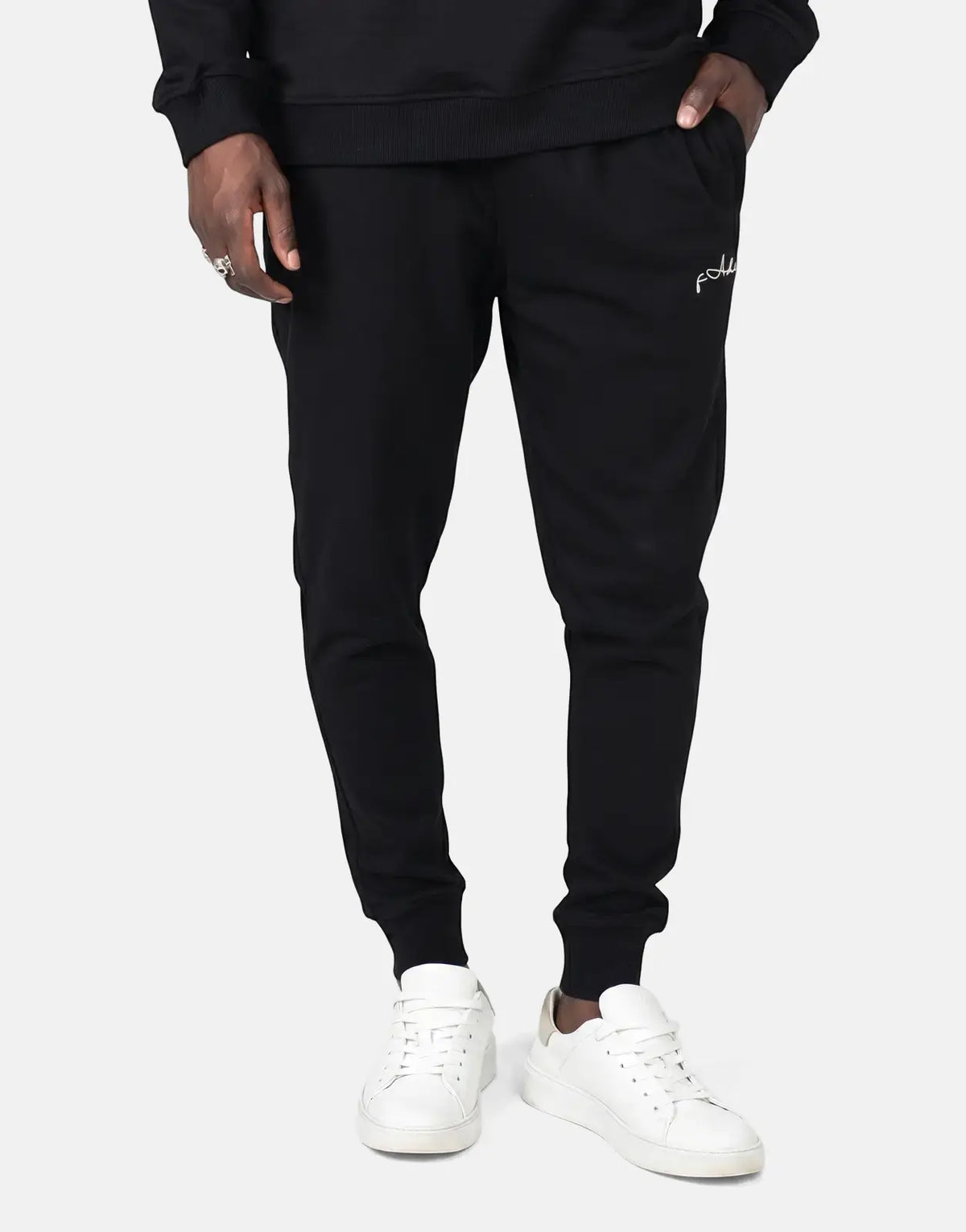 Black Fade Signature Sweatpants worn by a person, featuring a tapered fit, ribbed cuffs, and a white script logo on the