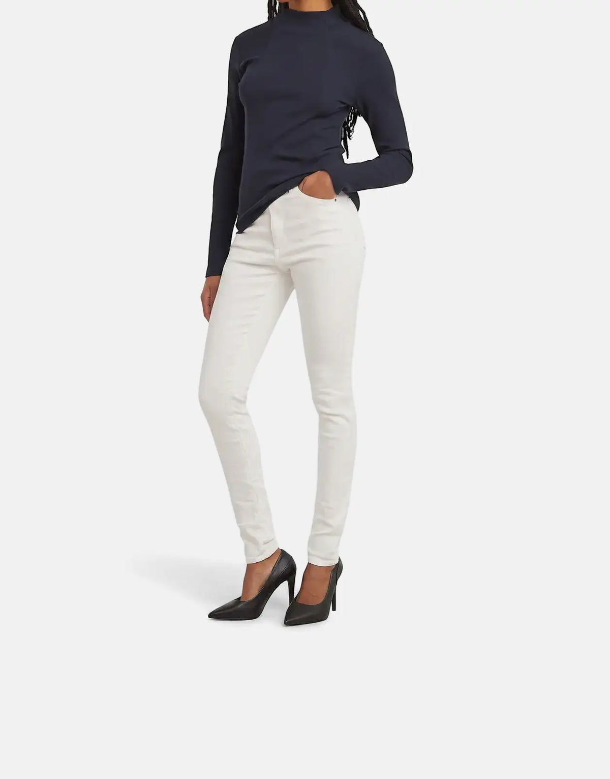 Woman wearing G-Star RAW Kafey Ultra High Skinny Rinsed Jeans and a dark blue mock neck top with black heels.