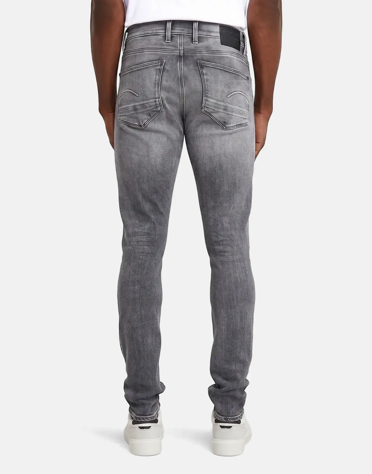 Men's G-Star RAW Revend FWD Skinny jeans in a faded shadow grey wash, shown from the back with white sneakers.