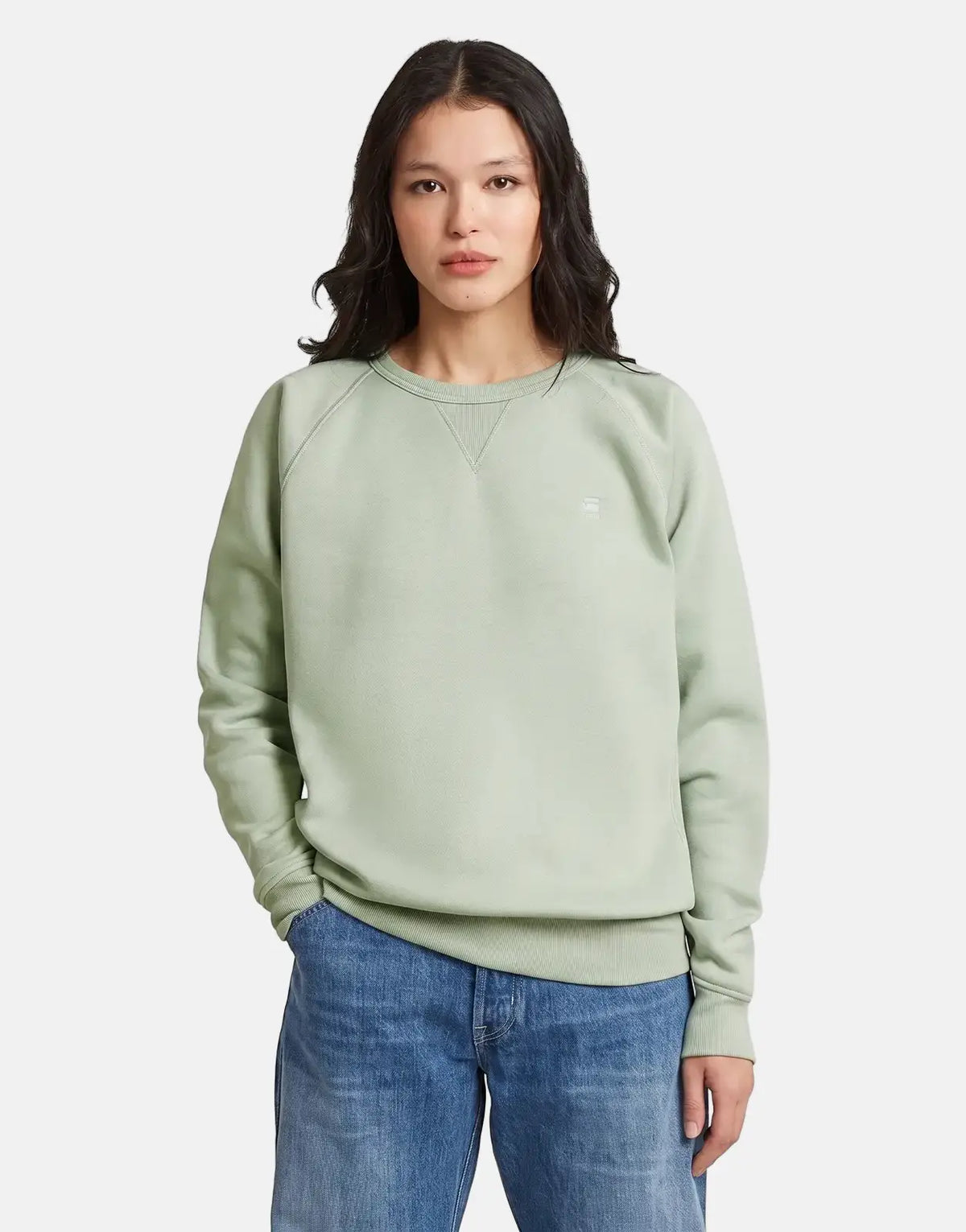 A woman models a pale green G-Star RAW Premium Core 2.0 t-shirt with blue jeans, captured waist-up.