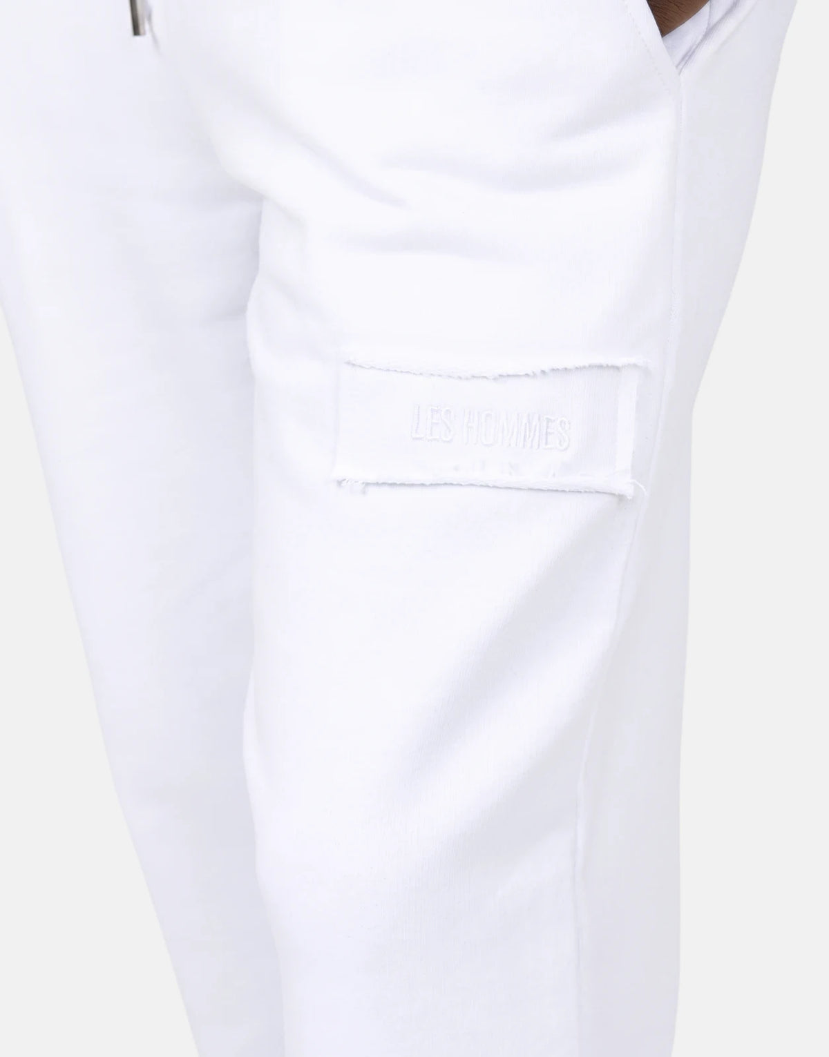 Close-up of Les Hommes White Jogger with a subtle tone-on-tone logo patch on the thigh, showcasing the soft fabric.